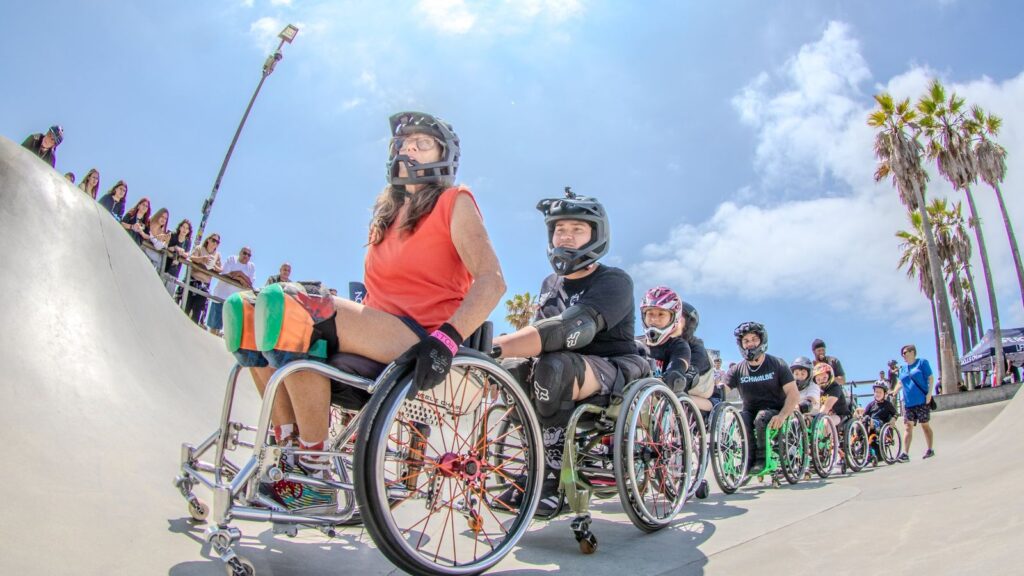 Adaptive wheelchair skaters lined up inside Venice Skate Park during a Life Rolls On event