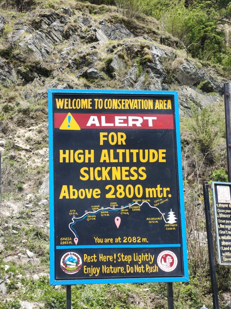 Sign warning of high altitude sickness above 2800 meters in a conservation area. Includes a map, elevation points, and safety advice. Rocky, green background. — Photo by shirishpoudel07