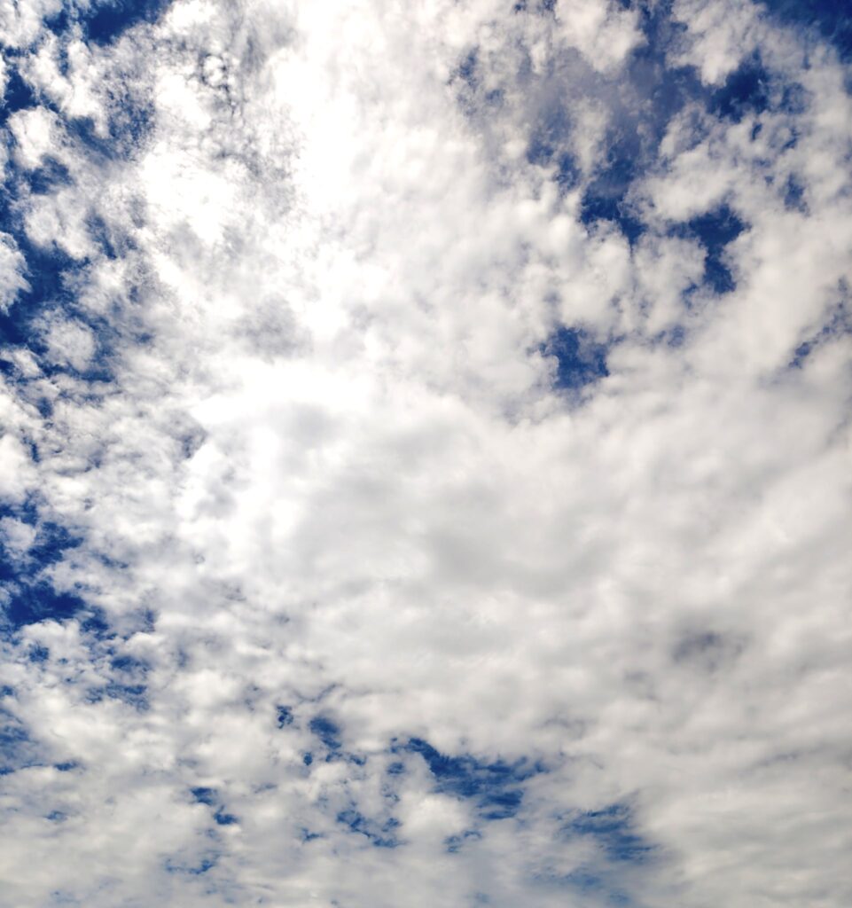 A wide view of the sky filled with a blend of white and gray clouds against a backdrop of deep blue. — Photo by shirishpoudel07