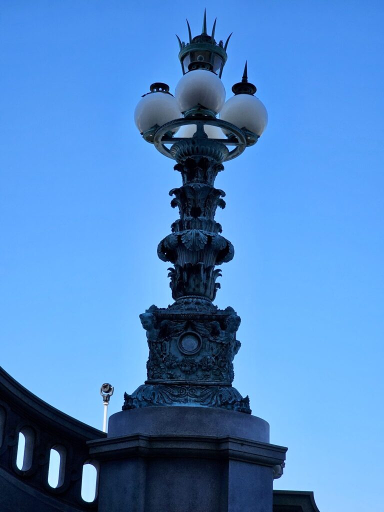 An antique bronze lamp post with intricate details stands against a deep blue sky, capturing timeless elegance in Washington, D.C. — Photo by Bigul Malayi